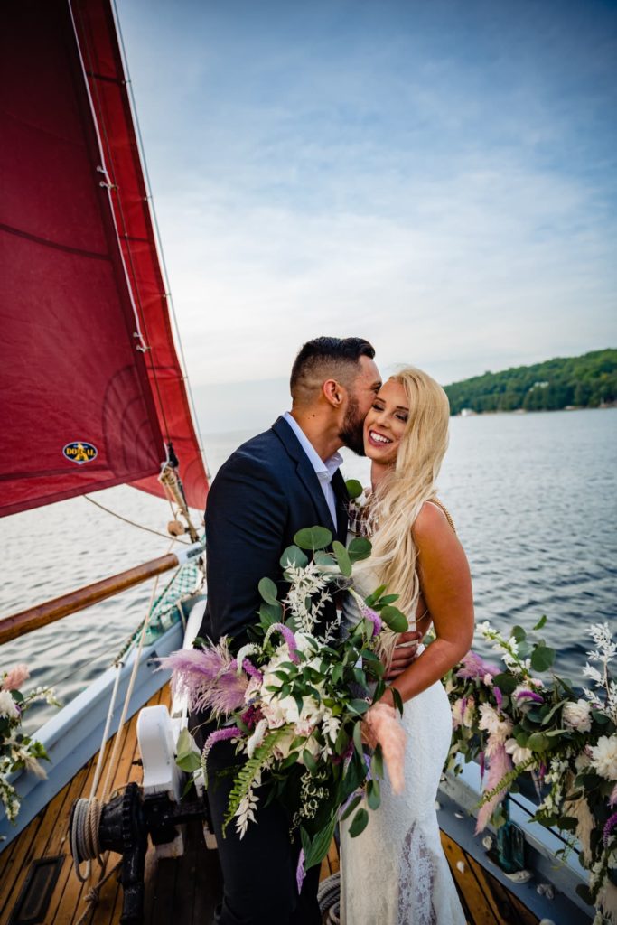 A couple elopes on a sailboat at sunset

