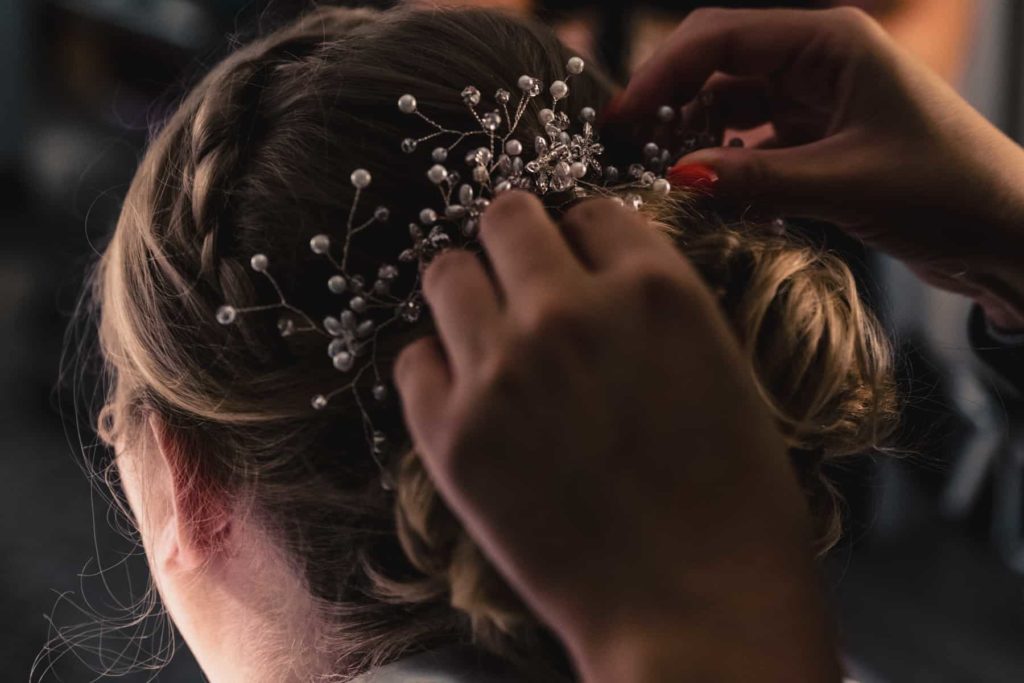 The hair stylist puts the finishing touches on Paiges beautiful wedding hairstyle.