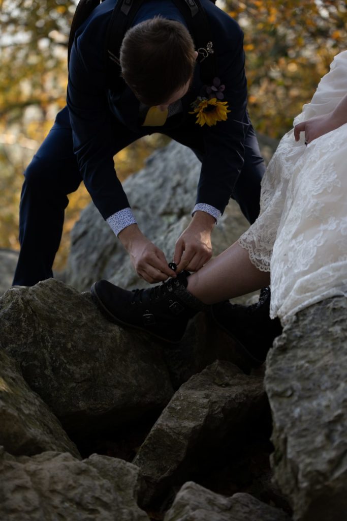 This bride wore hiking boots under her wedding dress. It's totally feasible to do and nobody who didn't know she was doing it would've had any idea. Here, the groom pauses to tie his bride's hiking boots as they hiked through this Pennsylvania mountain range.