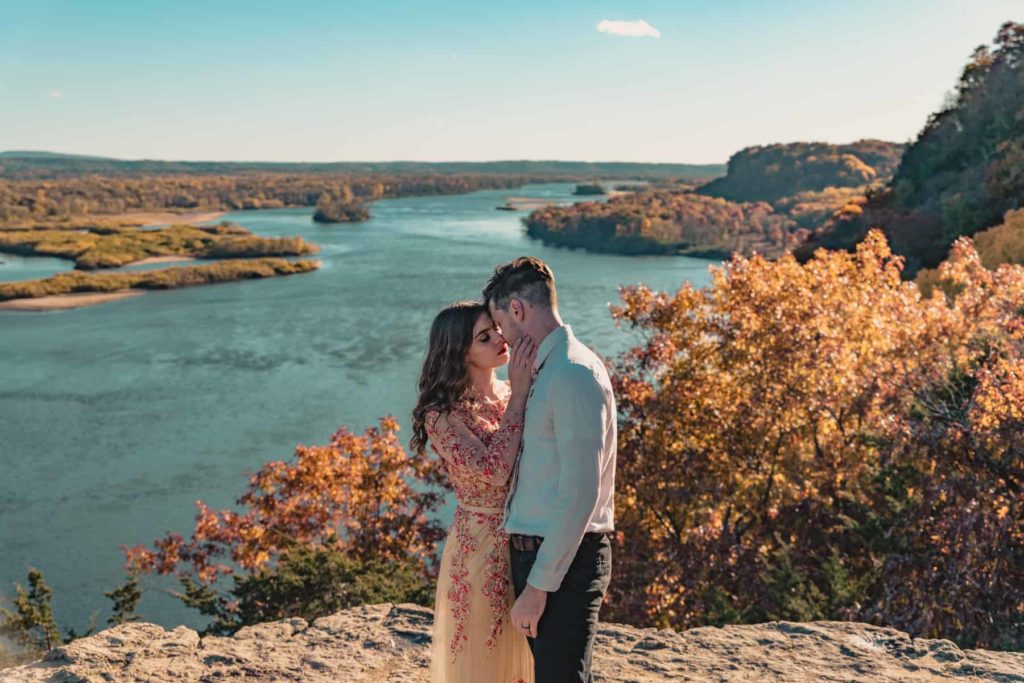 A couple gets close atop a Wisconsin clifftop during their Wisconsin vow renewal just before sunset with the leaves changing color in the fall