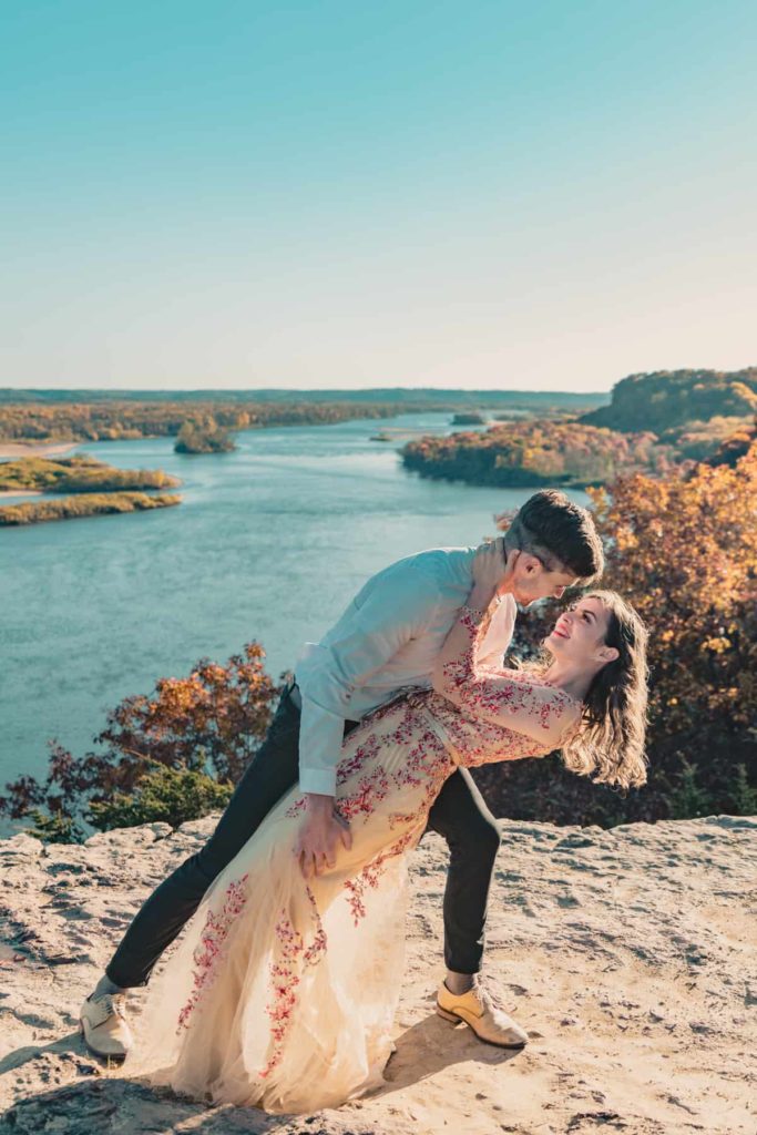 A groom dips his bride during this Wisconsin adventure elopement atop a cliff in south central Wisconsin
