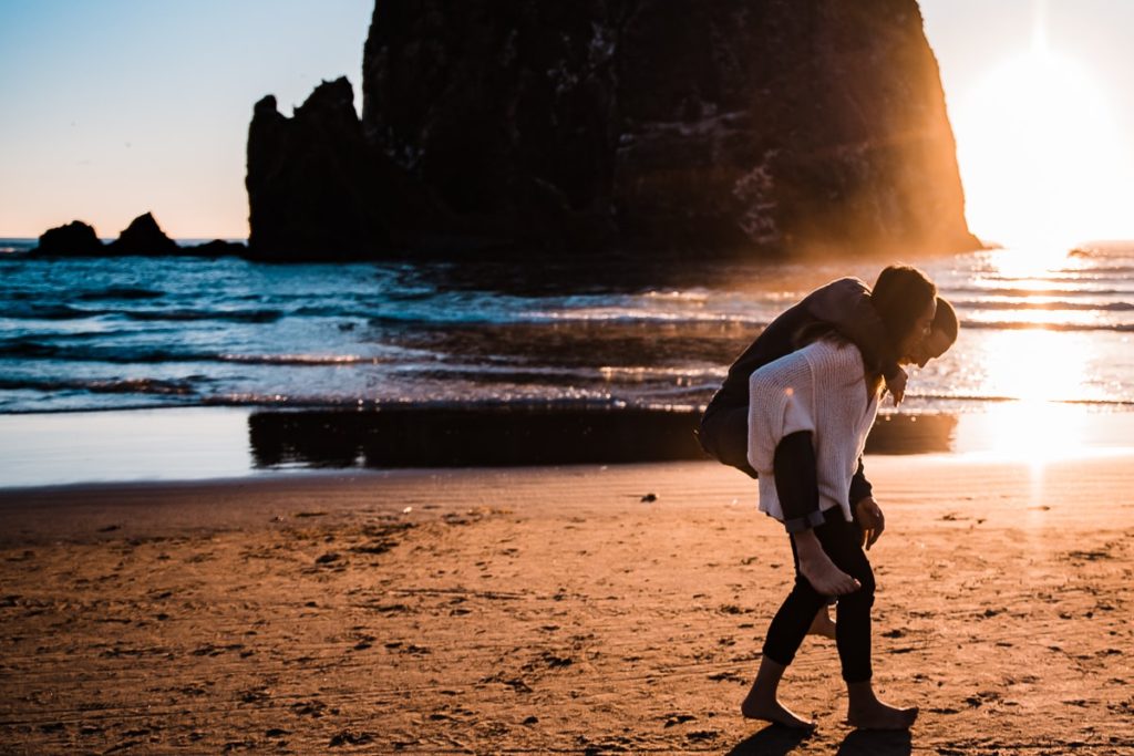  He gives her a piggyback ride at their engagement session at Cannon Beach on the Oregon Coast