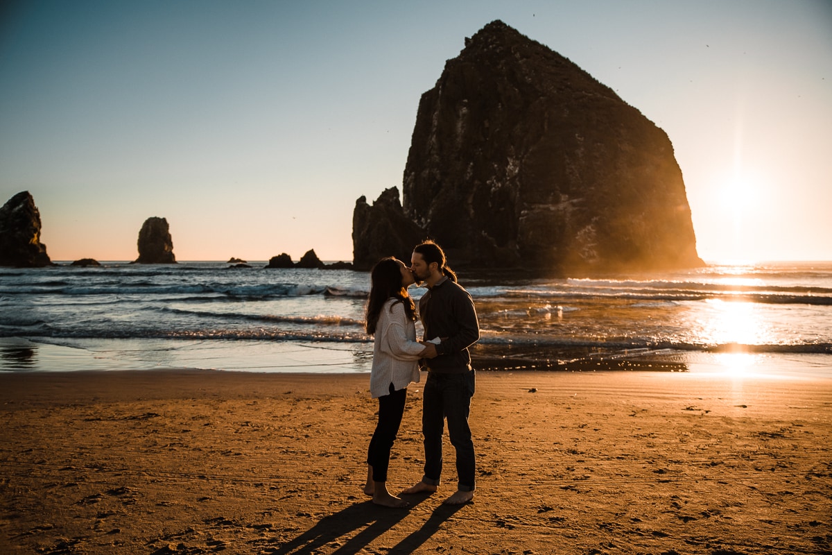 Kissing in front of Haystack Rock on Cannon Beach during the engagement session on the Oregon Coast