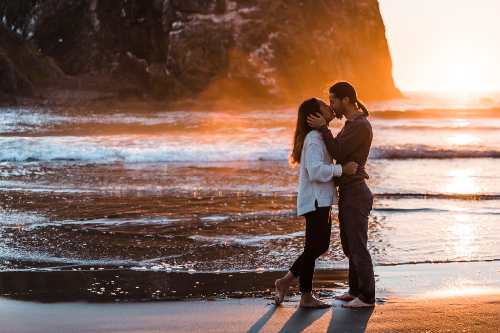 An engaged couple kisses on Cannon Beach at sunset on the Oregon Coast